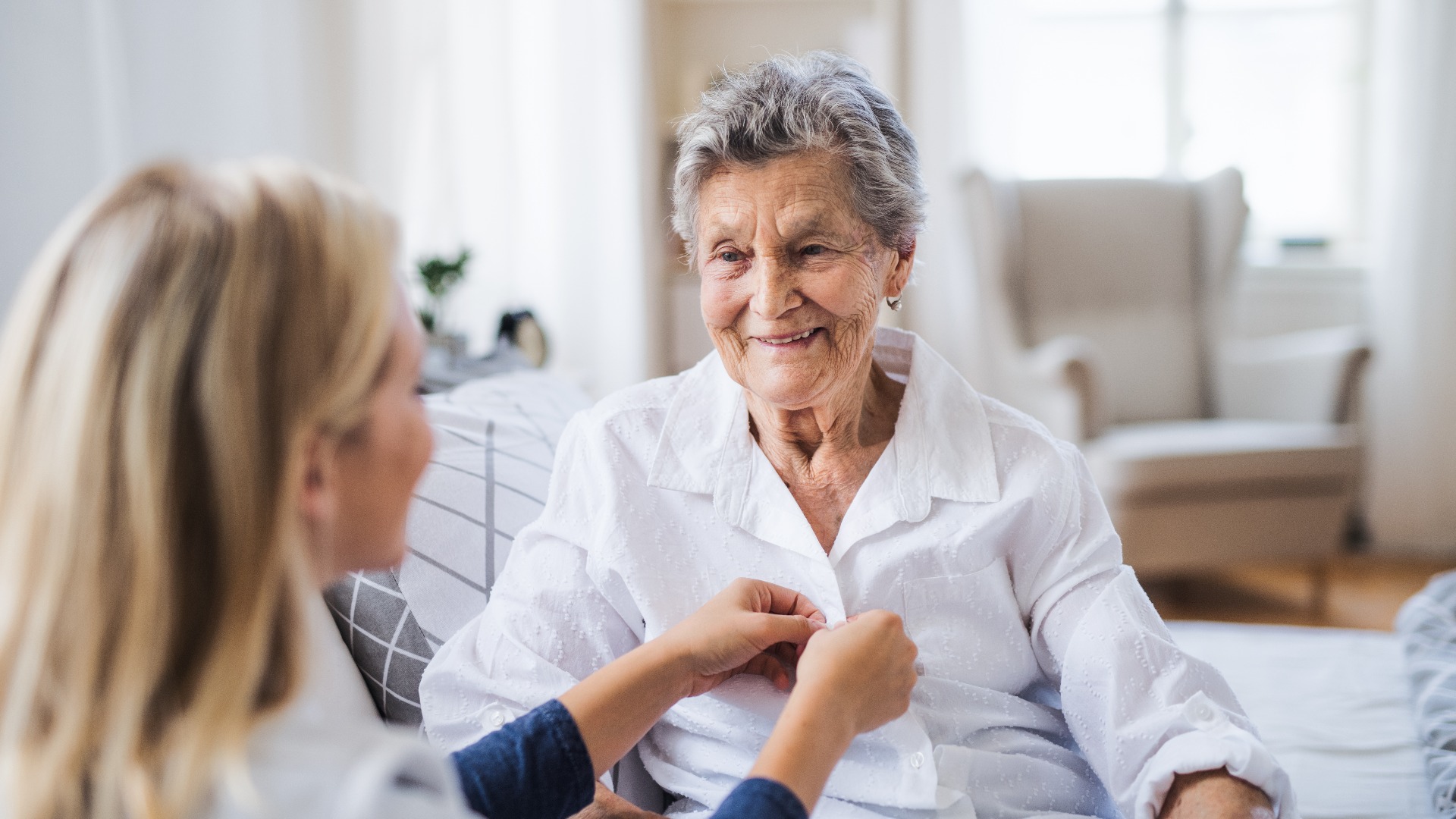 Eine Gesundheitsberaterin hilft einer kranken älteren Frau, die zu Hause im Bett sitzt.